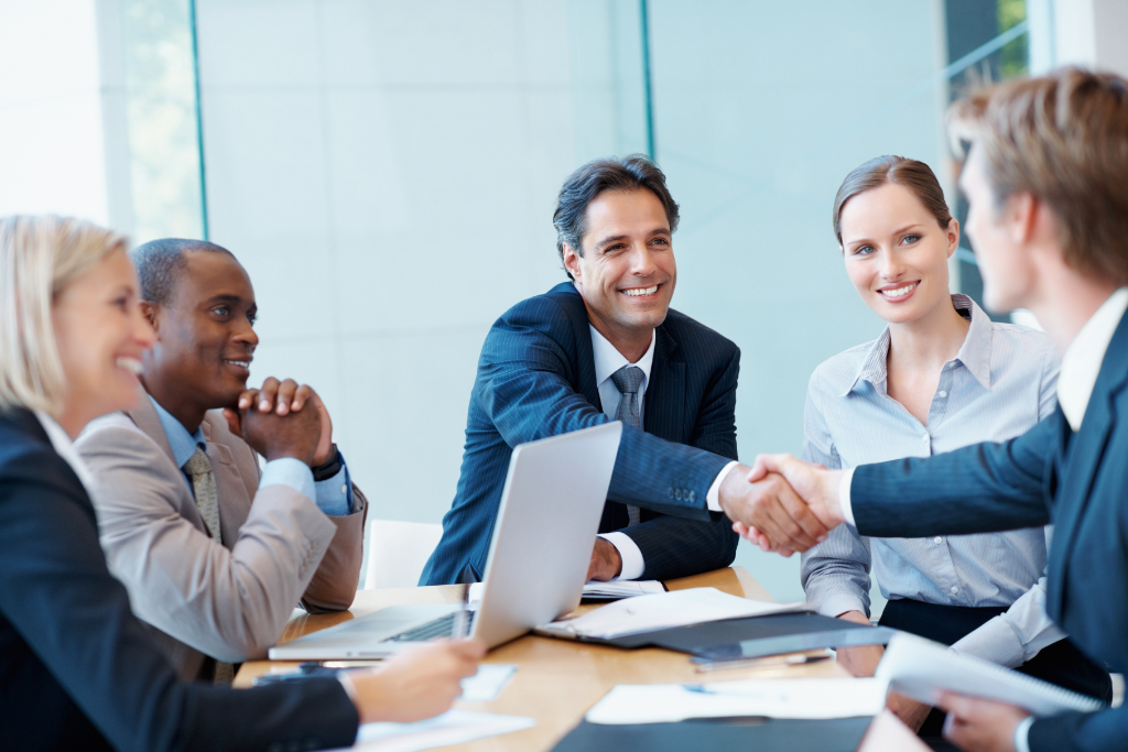 A business team shaking hands in a meeting, reflecting collaboration and strong leadership in strategy execution.